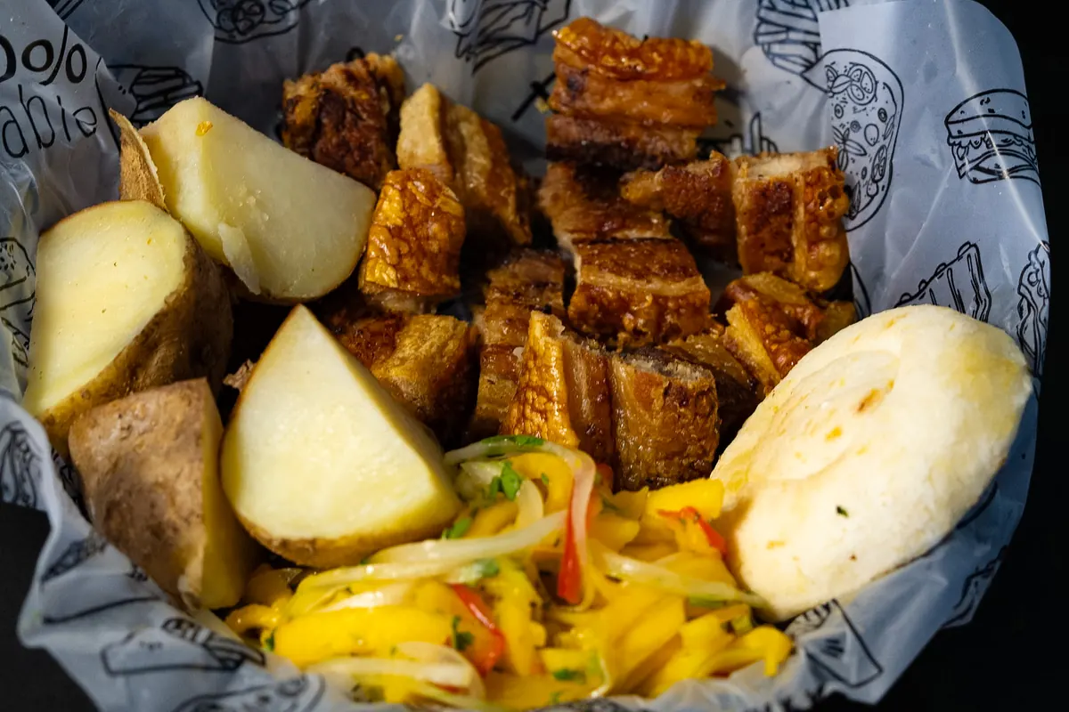 Chicharrón en trozos con papas, arepa y ensalada de mango