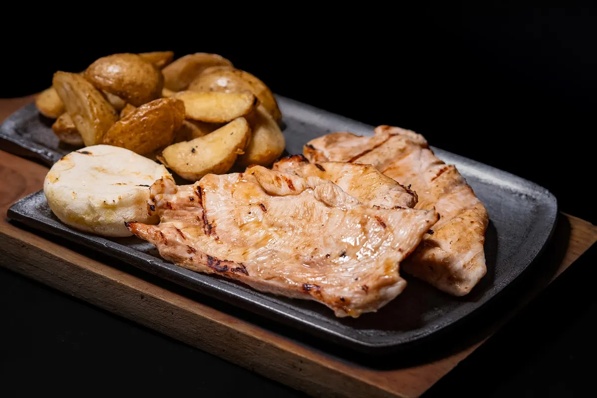 Filete de pollo a la plancha con papas en cascos y arepa